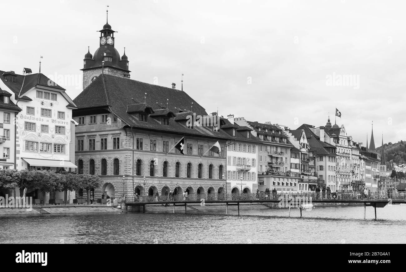 Lucerne, Switzerland - May 7, 2017: Coastal landscape with old Town Hall clock tower on a background. Ordinary people walk the street . Black and whit Stock Photo