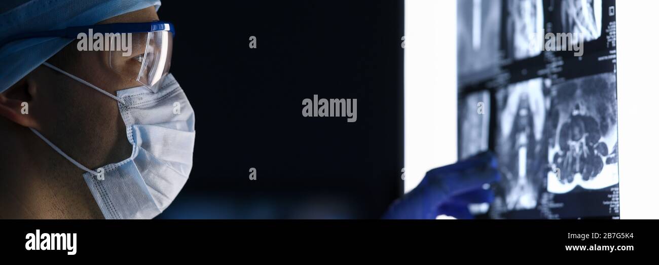 Male doctor in surgical clothes looking at vertebral mri scan Stock