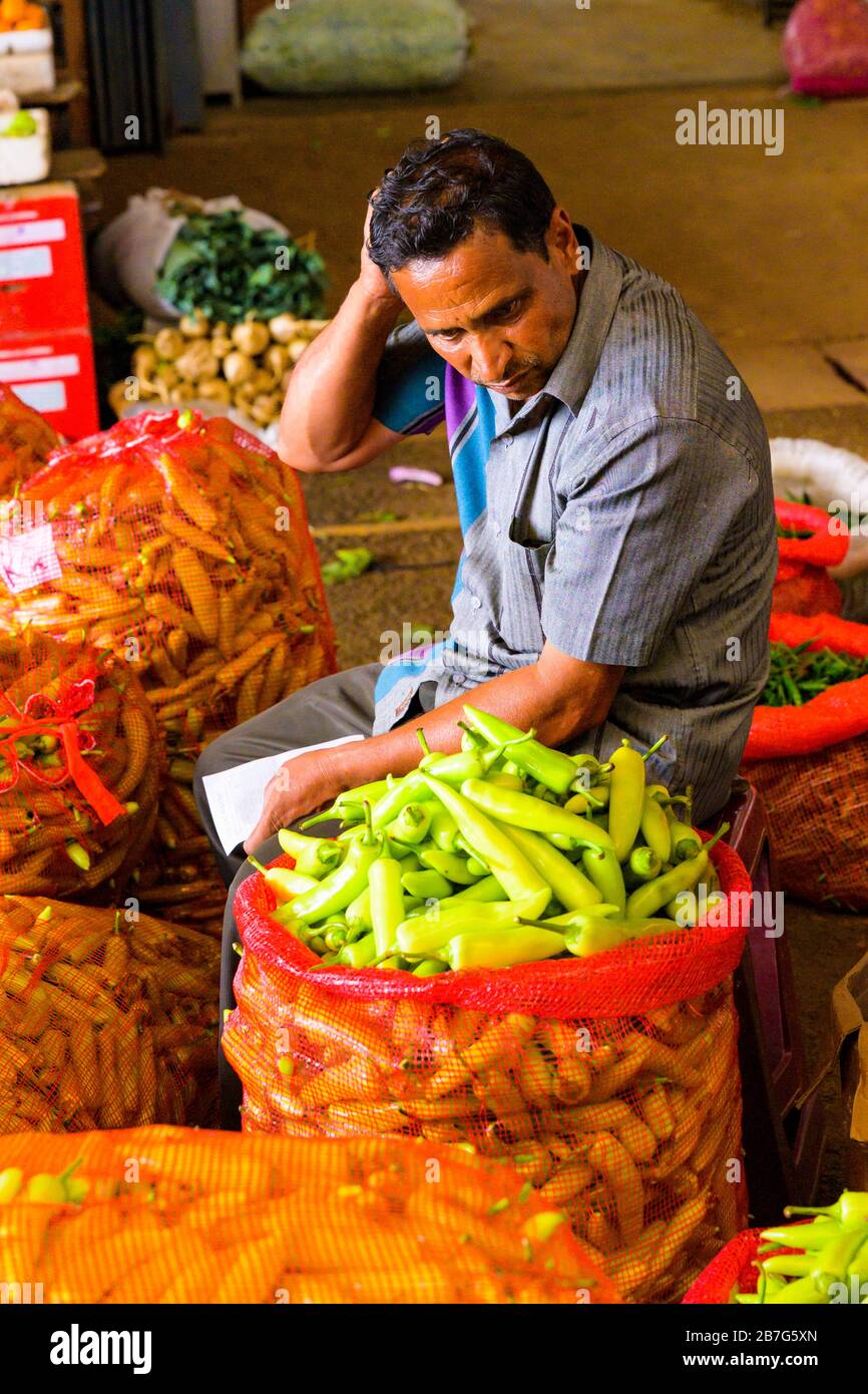 Sri Lanka Ceylon Dambulla Economic Centre Center wholesale vegetable & fruit market sacks vendor surrounded red sacks large green peppers chillis Stock Photo