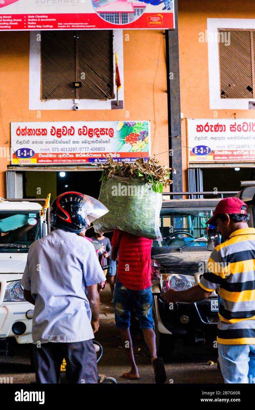 South Asia Sri Lanka Ceylon Dambulla Economic Centre Center wholesale vegetable & fruit market porter white sack on shoulder greens shops stores Stock Photo
