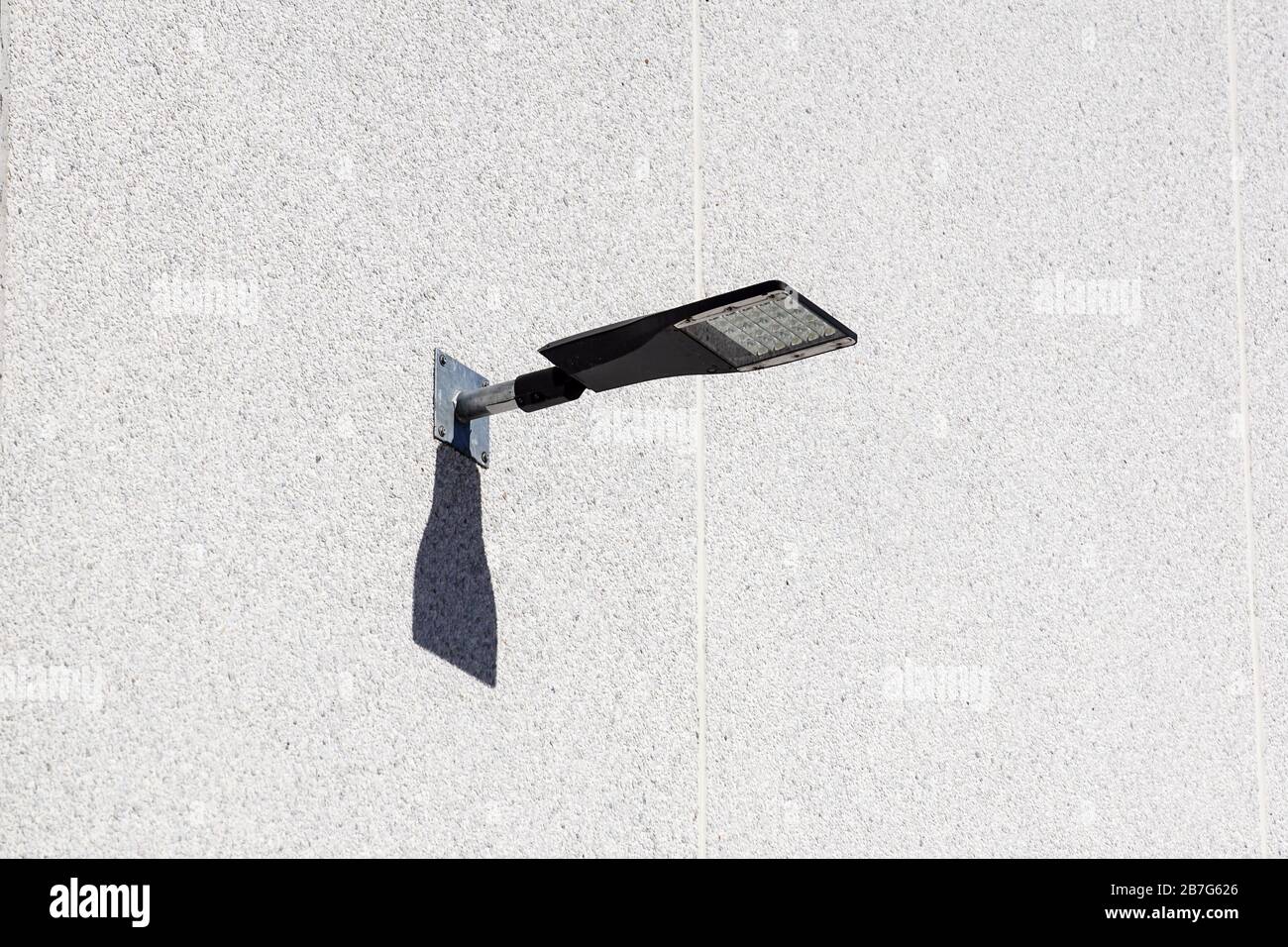 LED fixed on to a bend lamp post in front of a building. The lamp post