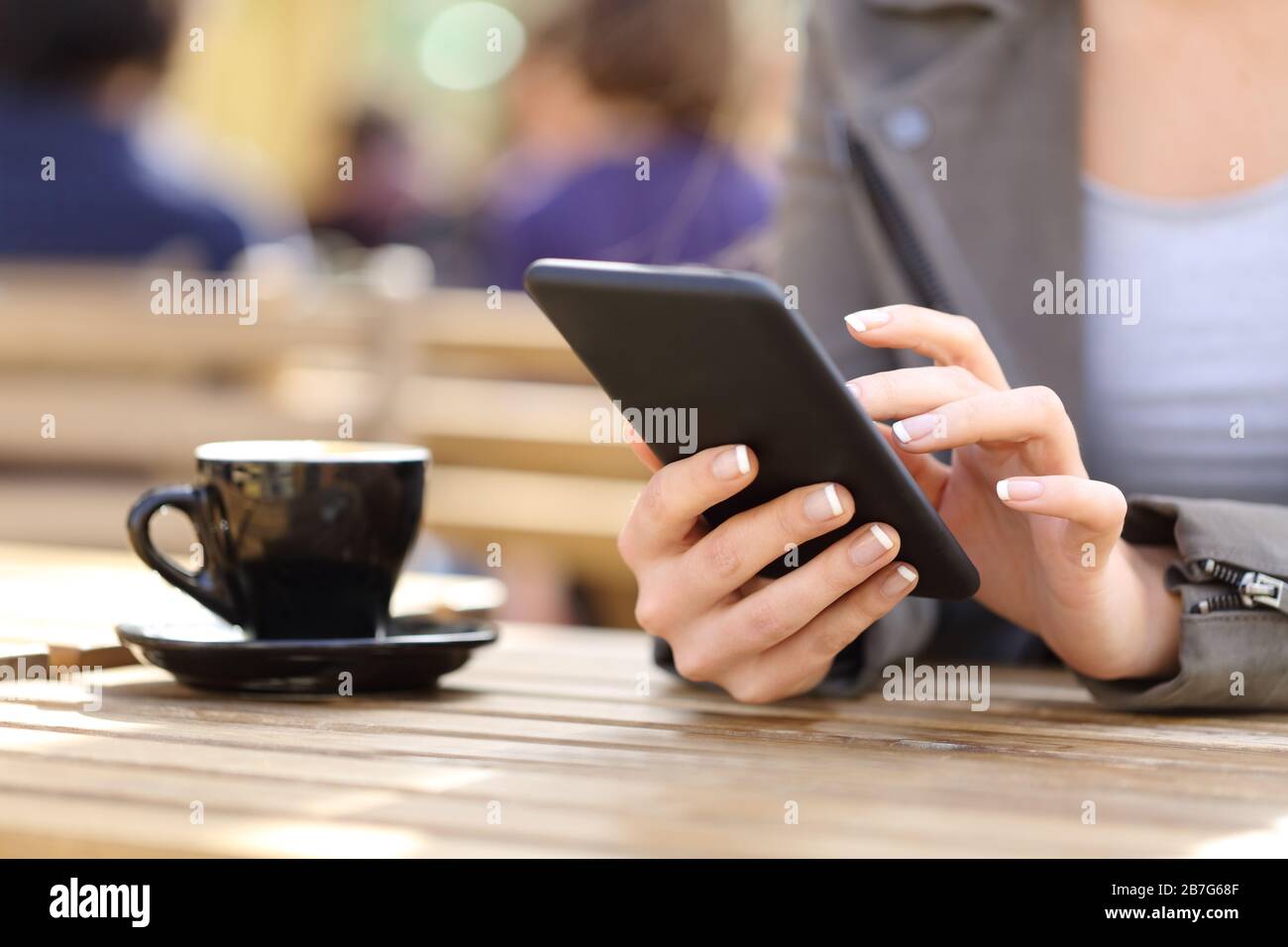 Close up of woman hands using her cell phone on a cafe terrace Stock Photo