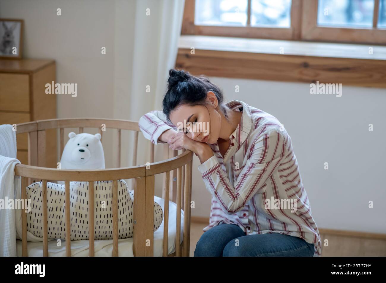 Sleepy and tired mom resting her head on the cot Stock Photo Alamy