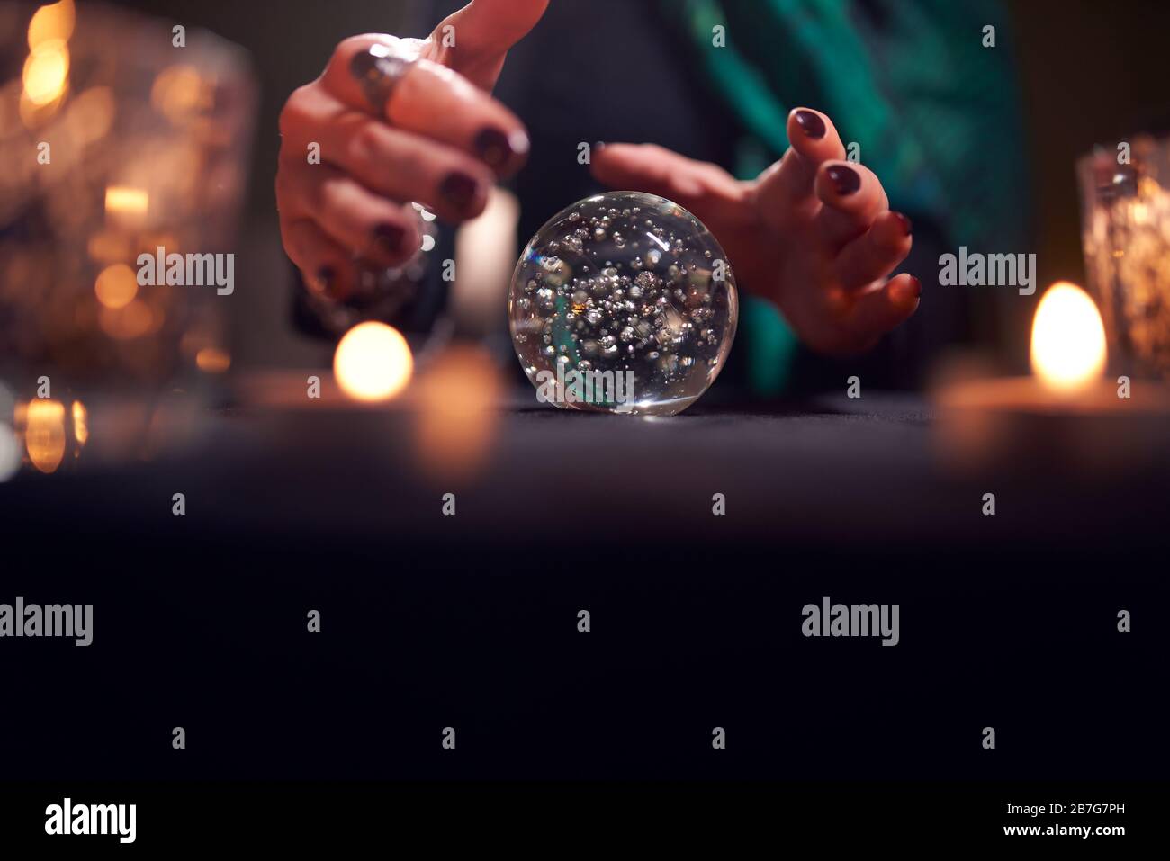 Hands of unrecognizable fortune-teller with ball of predictions in dark room Stock Photo