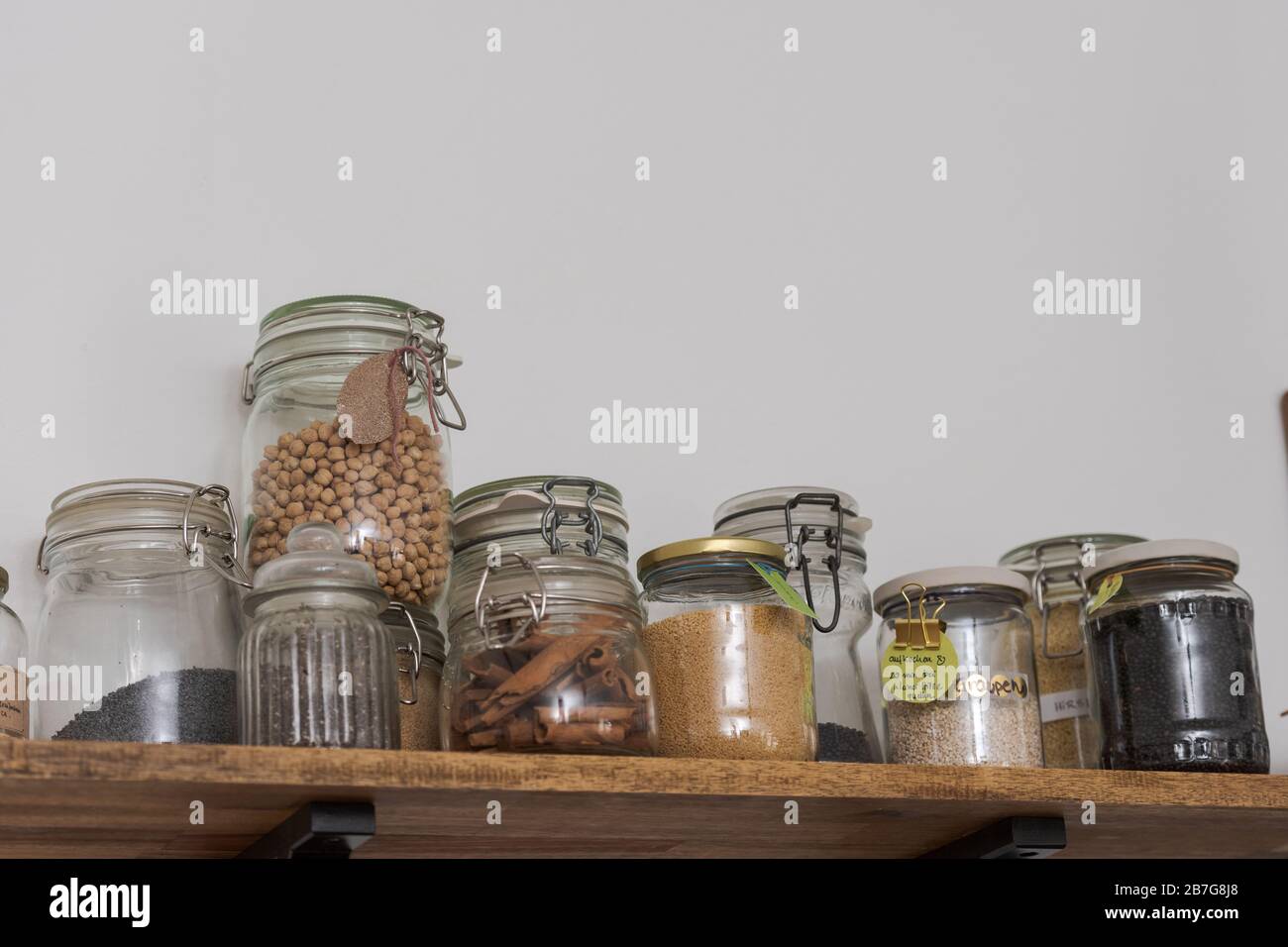 Low angle view of glass jars filled with various food supplies standing on wooden board in kitchen Stock Photo