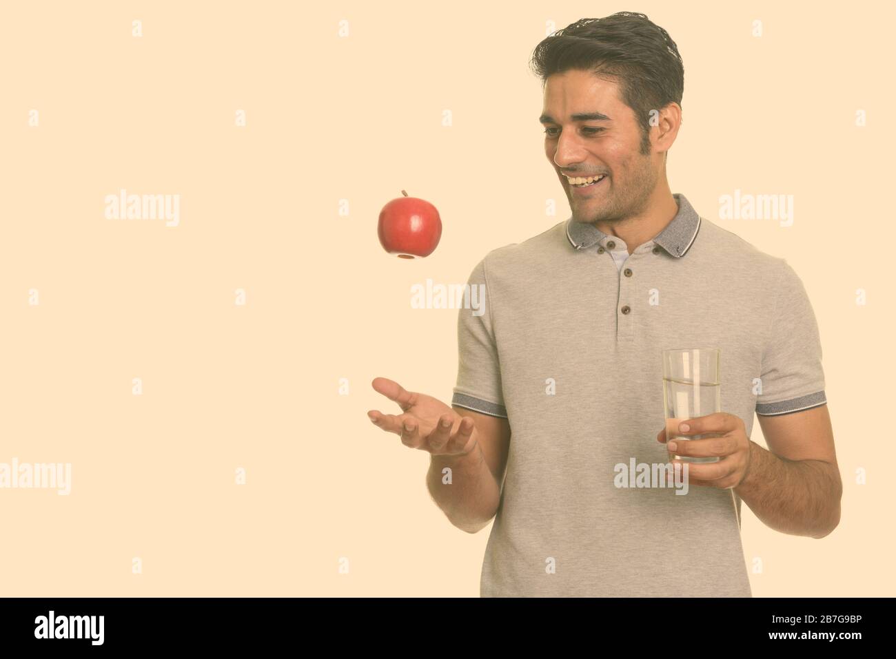 Young happy Persian man holding red apple and glass of water Stock ...