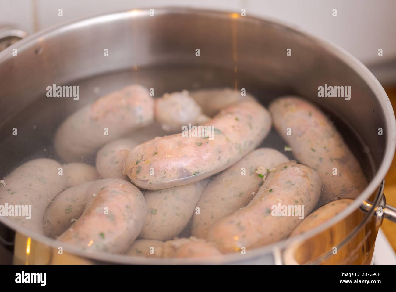 Making bavarian white sausages at home, chain of sausages  boiling in pot with hot water Stock Photo
