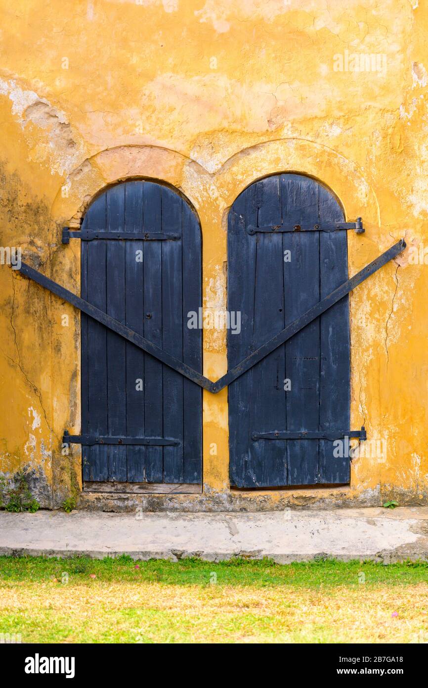 South Asia Sri Lanka Fort Galle colonial centre old ancient harbour port town wall bastion window shutters metal bars grass verge yellow plaster wall Stock Photo
