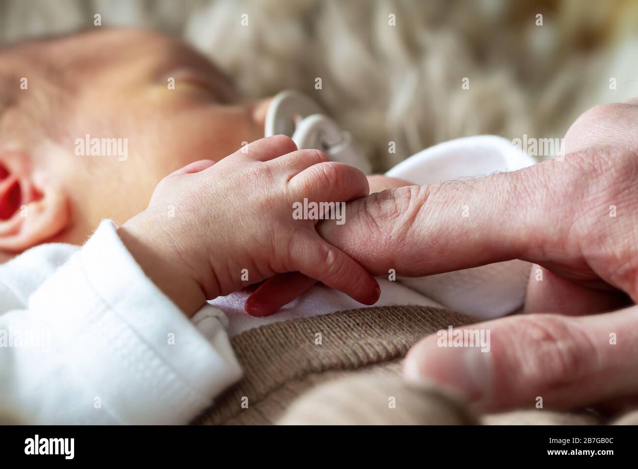 Parents holding hands of their newborn baby ( One week old ) Stock Photo