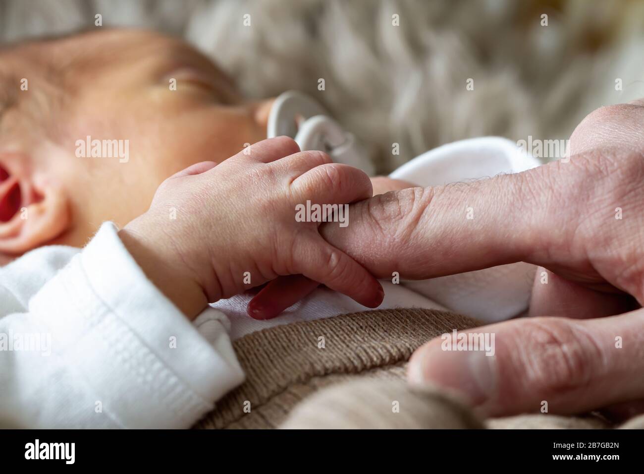 Parents holding hands of their newborn baby ( One week old ) Stock Photo