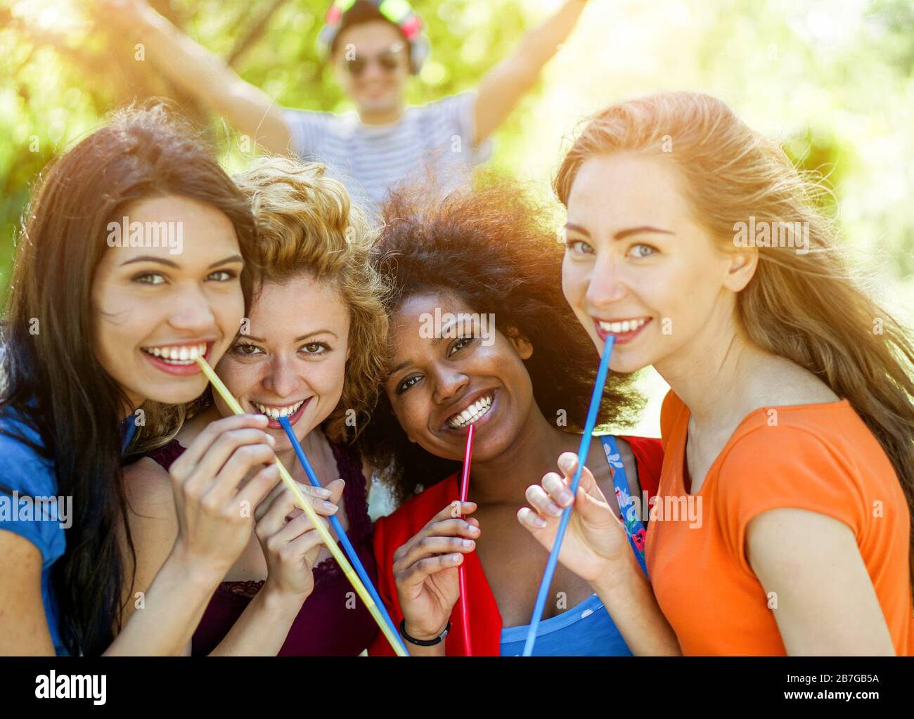 Happy diverse ethnic friends drinking cocktail in summer party outdoor - Young women having fun with dj set- Friendship,vacation and party concept - F Stock Photo