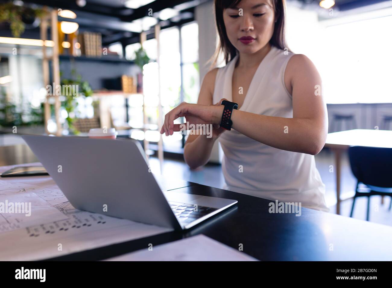Asian business woman looking her digital watch in office Stock Photo