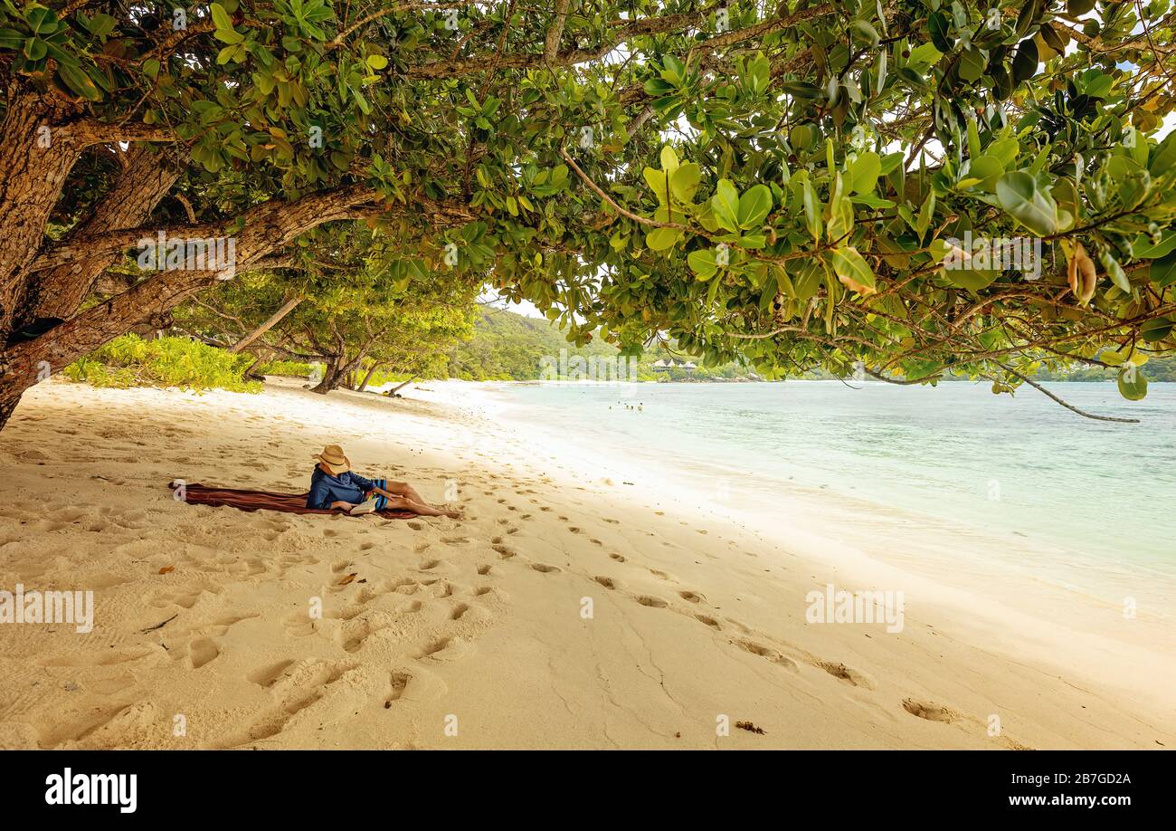 Handsome man lying on the beach and reading book. Summer time. Tourist relaxing on a tropical beach Stock Photo
