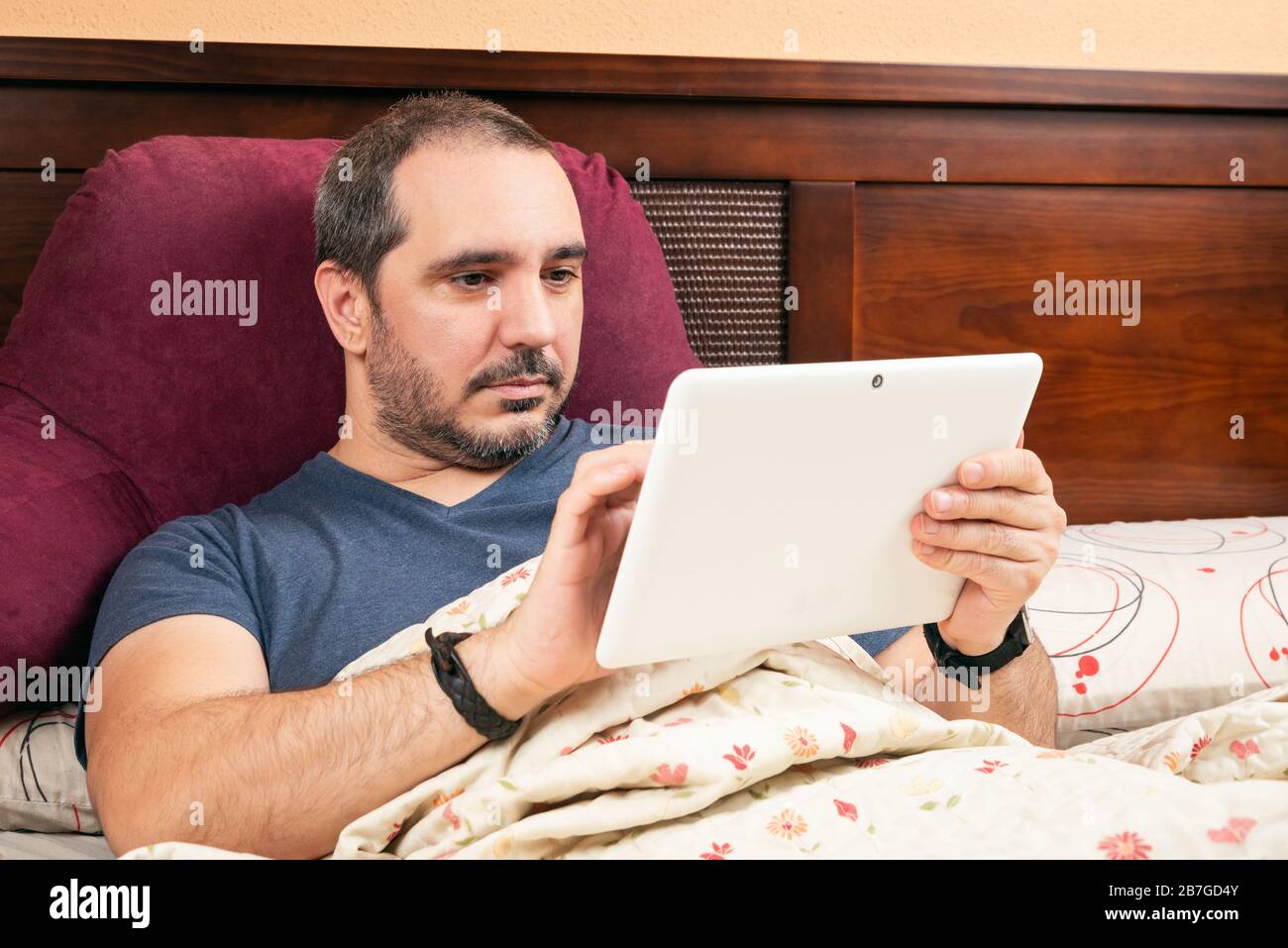 ill man using tablet in the bed. Stock Photo