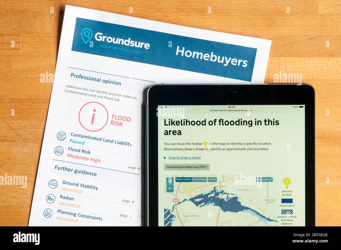 Assessing flood risk before buying a new house - flood risk report and government flood map displayed on ipad. Stock Photo
