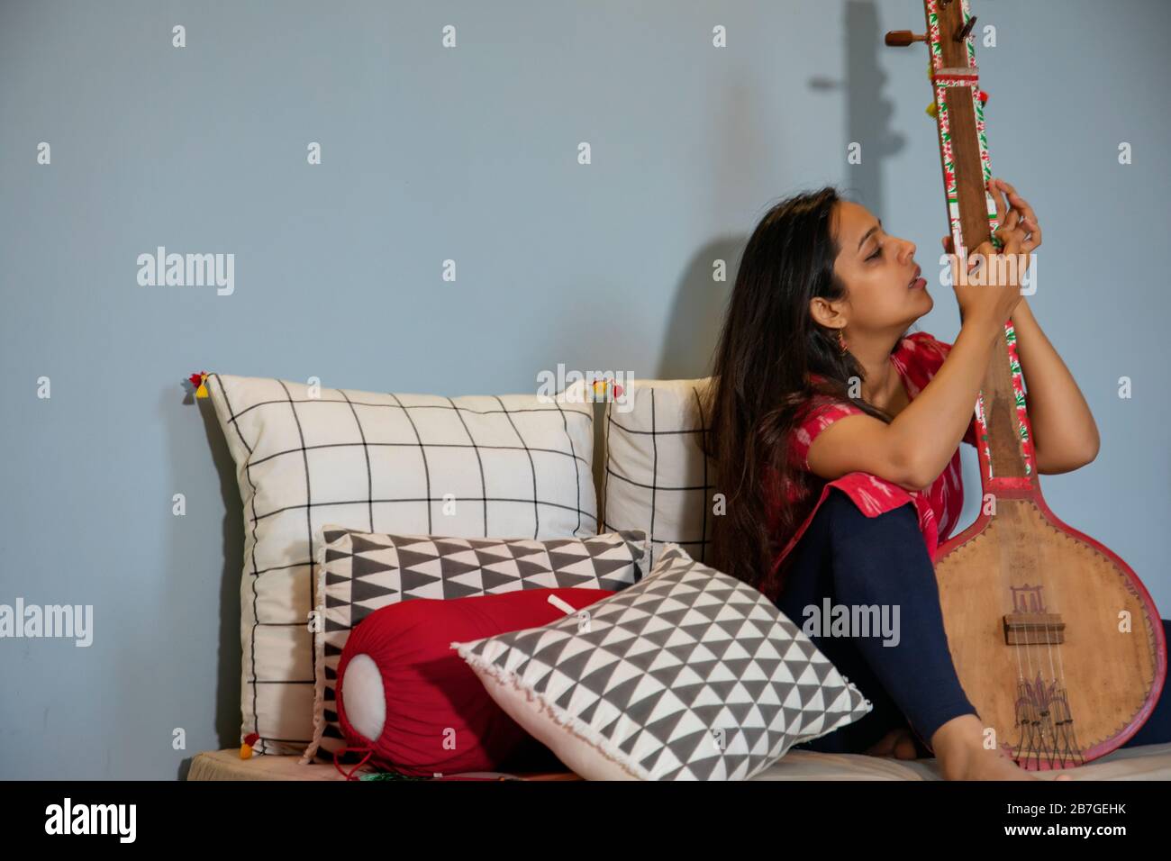 Woman playing tambura in her living room Stock Photo Alamy