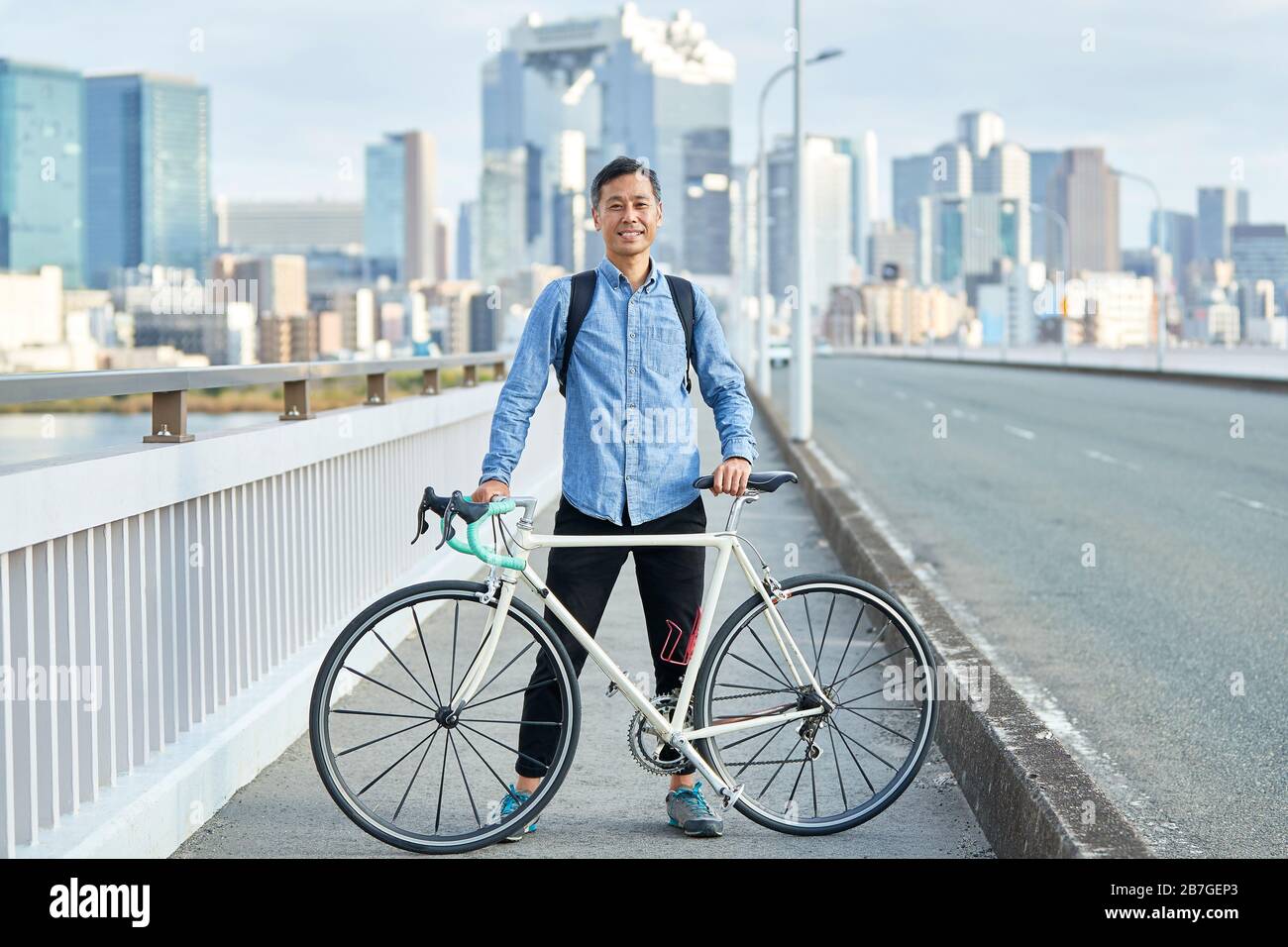 Mature Japanese man with bike downtown Osaka, Japan Stock Photo
