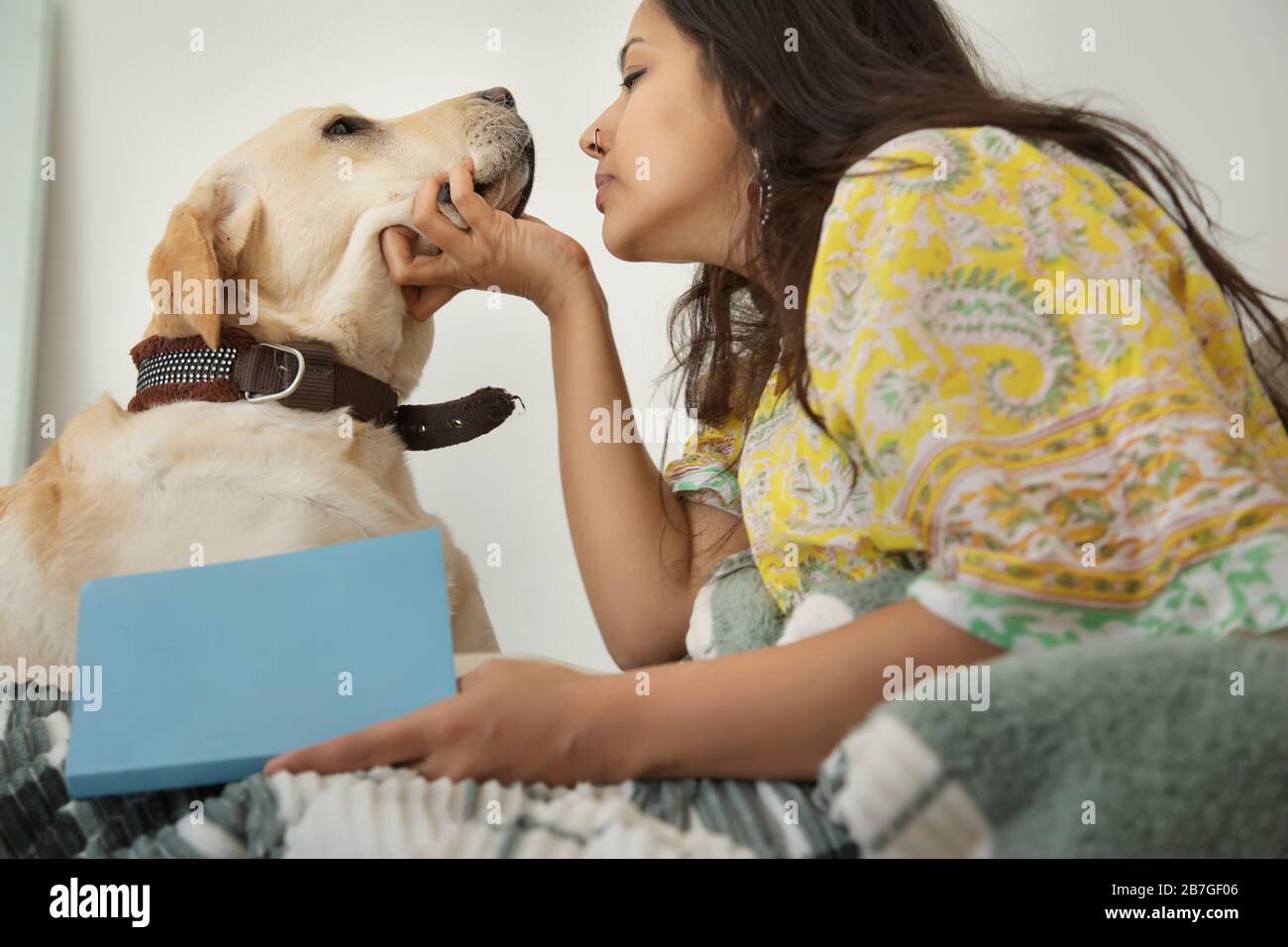Woman sitting with a book in her hand while pampering her dog. Stock Photo
