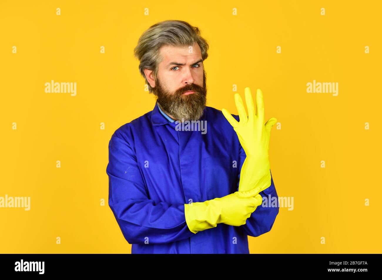 bearded man wear rubber gloves. mature janitor in uniform yellow