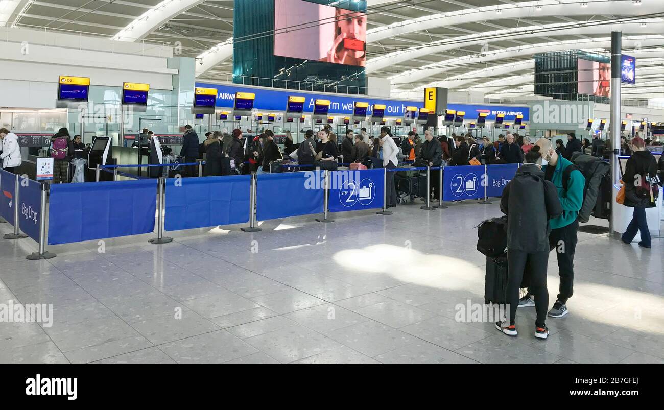 Passengers seek information at British Airways desks at Terminal Five of London's Heathrow Airport after flight schedules were slashed by the airline's parent company IAG. Stock Photo