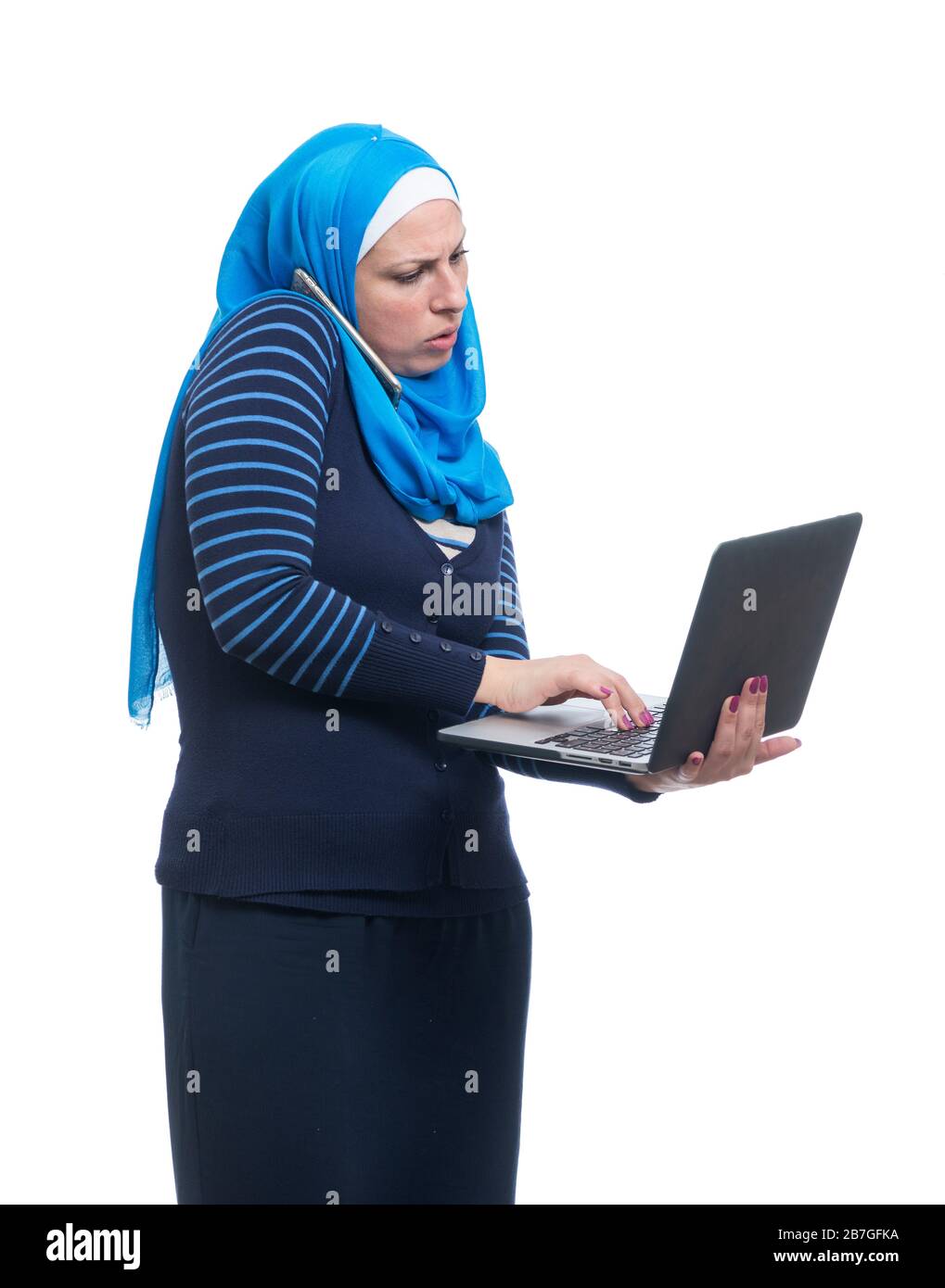 Muslim arab woman talking on mobile phone and using laptop. Multitasking Concept Stock Photo