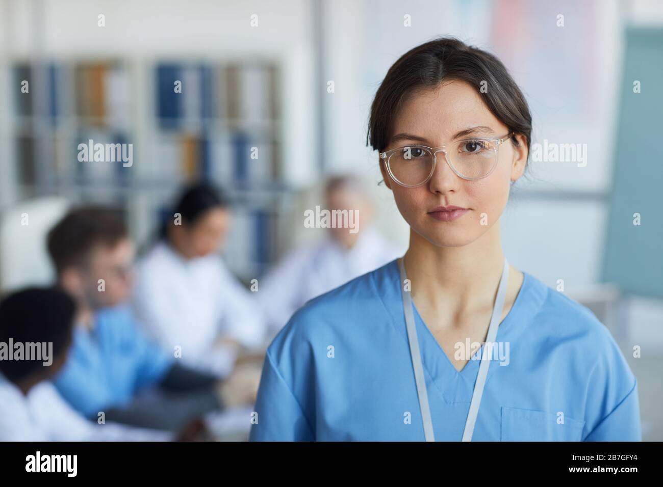 Head and shoulders portrait of young female nurse wearing glasses