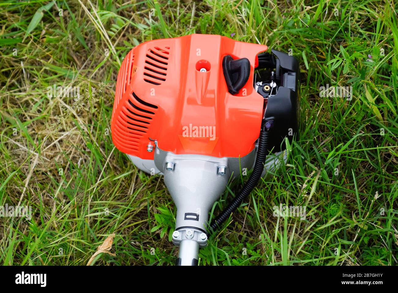 The engine of a gas trimmer lies on the grass. Power part of the trimmer. Trimer gascosis with a