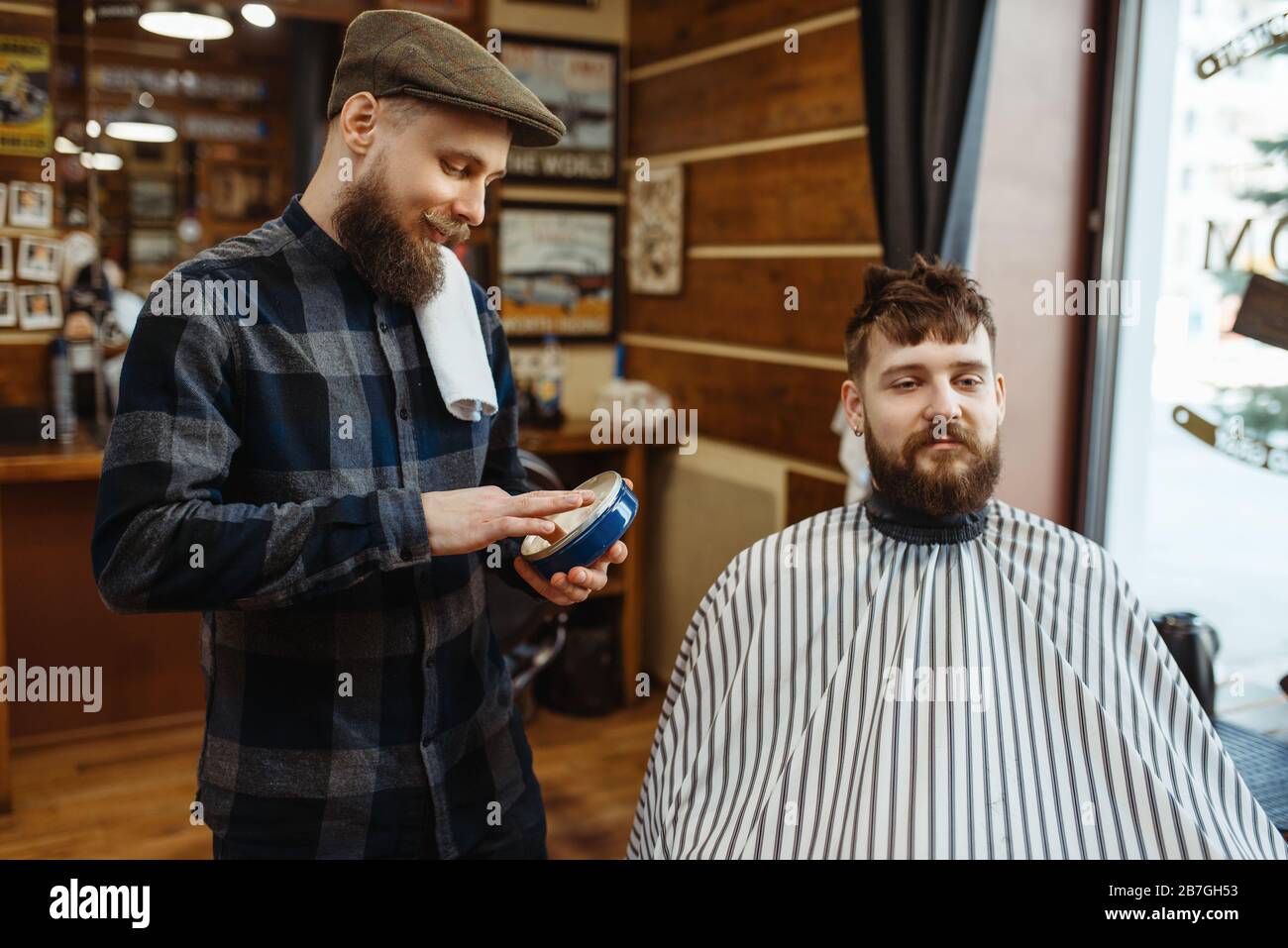 Barber in hat and bearded customer, Stock Photo Alamy