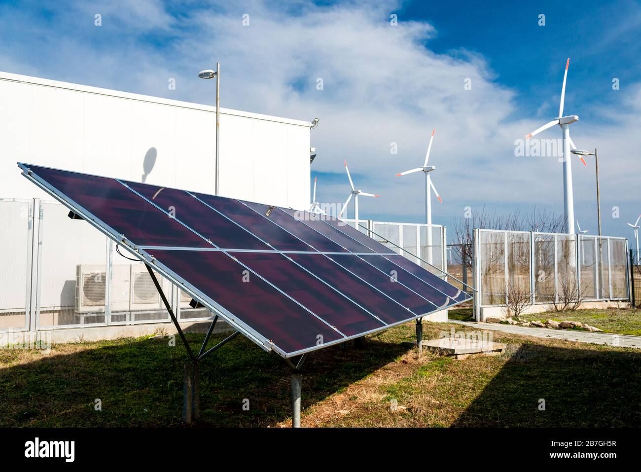 Solar panels in power station against wind turbines background ...