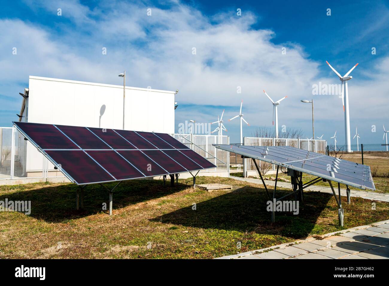 Solar panels in power station against wind turbines background ...