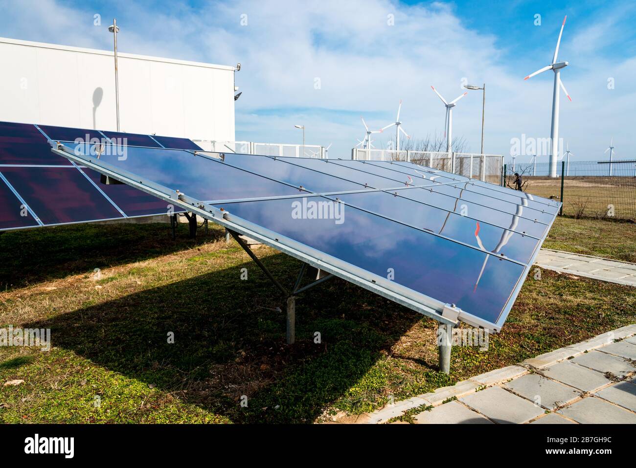 Solar panels in power station against wind turbines background ...