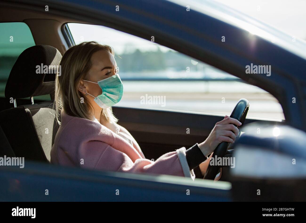 Woman in protective mask driving a car on road. Safe traveling Stock Photo  - Alamy