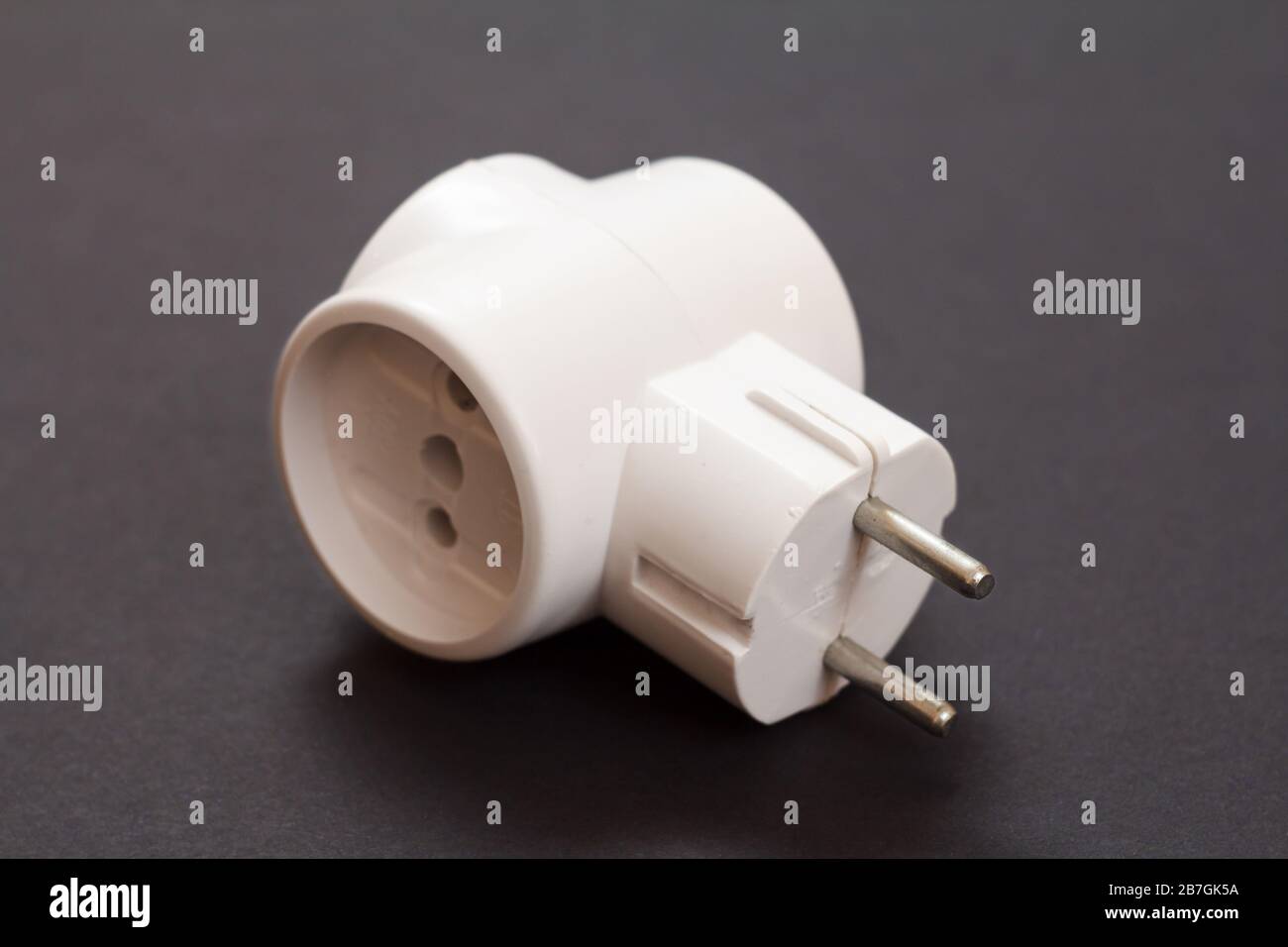 White plastic electrical tee connector with three sockets on a black background. Stock Photo