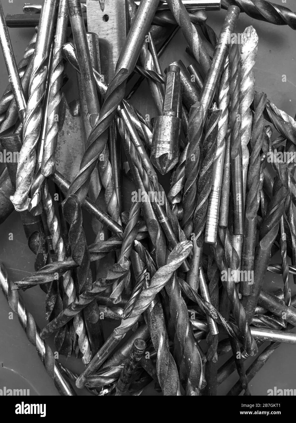 Used drill bits in a pile. A cutting tool for making holes in materials with power or hand drills. A collection found in a garage during a DIY session Stock Photo