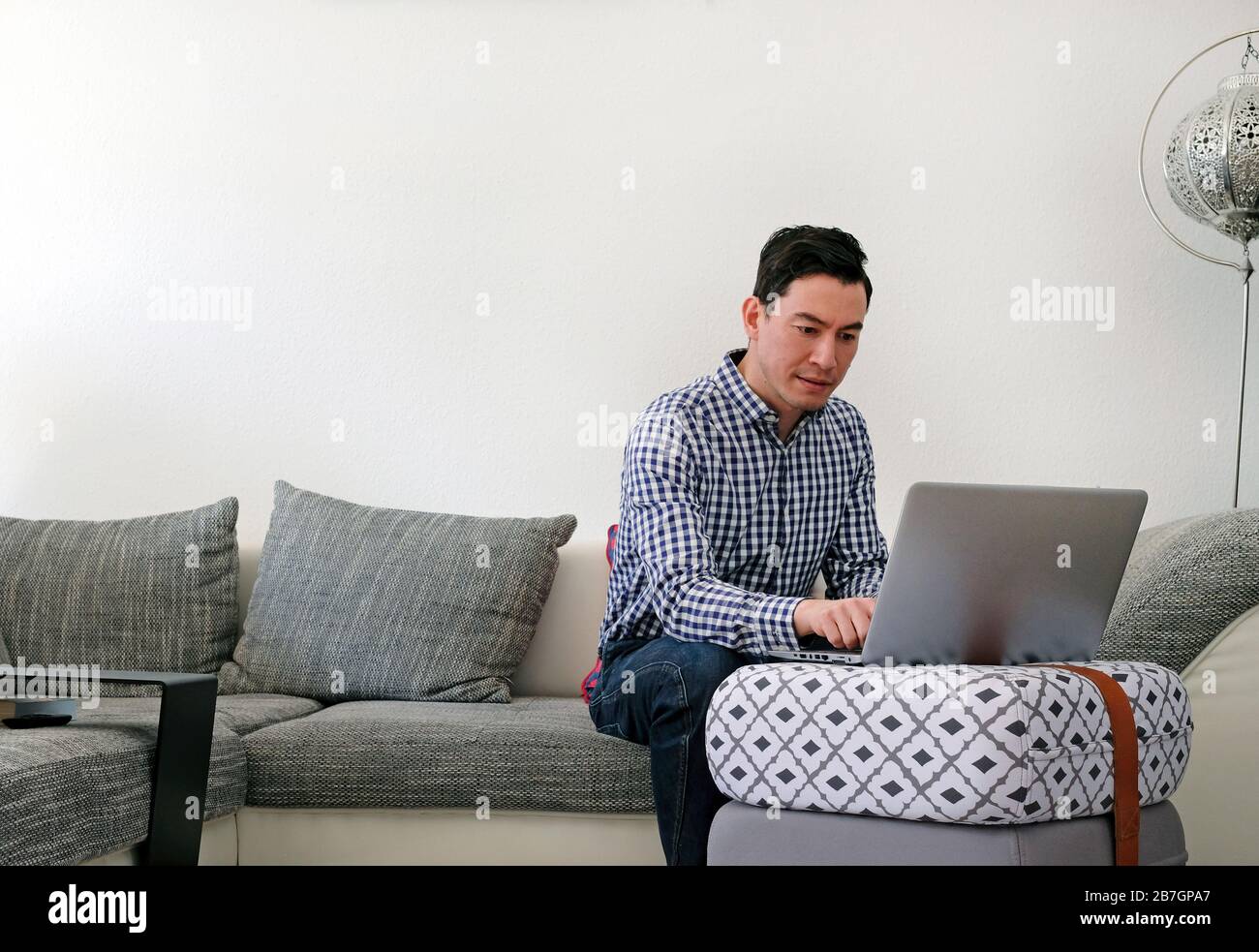 Man working from home with a laptop in the living room Stock Photo