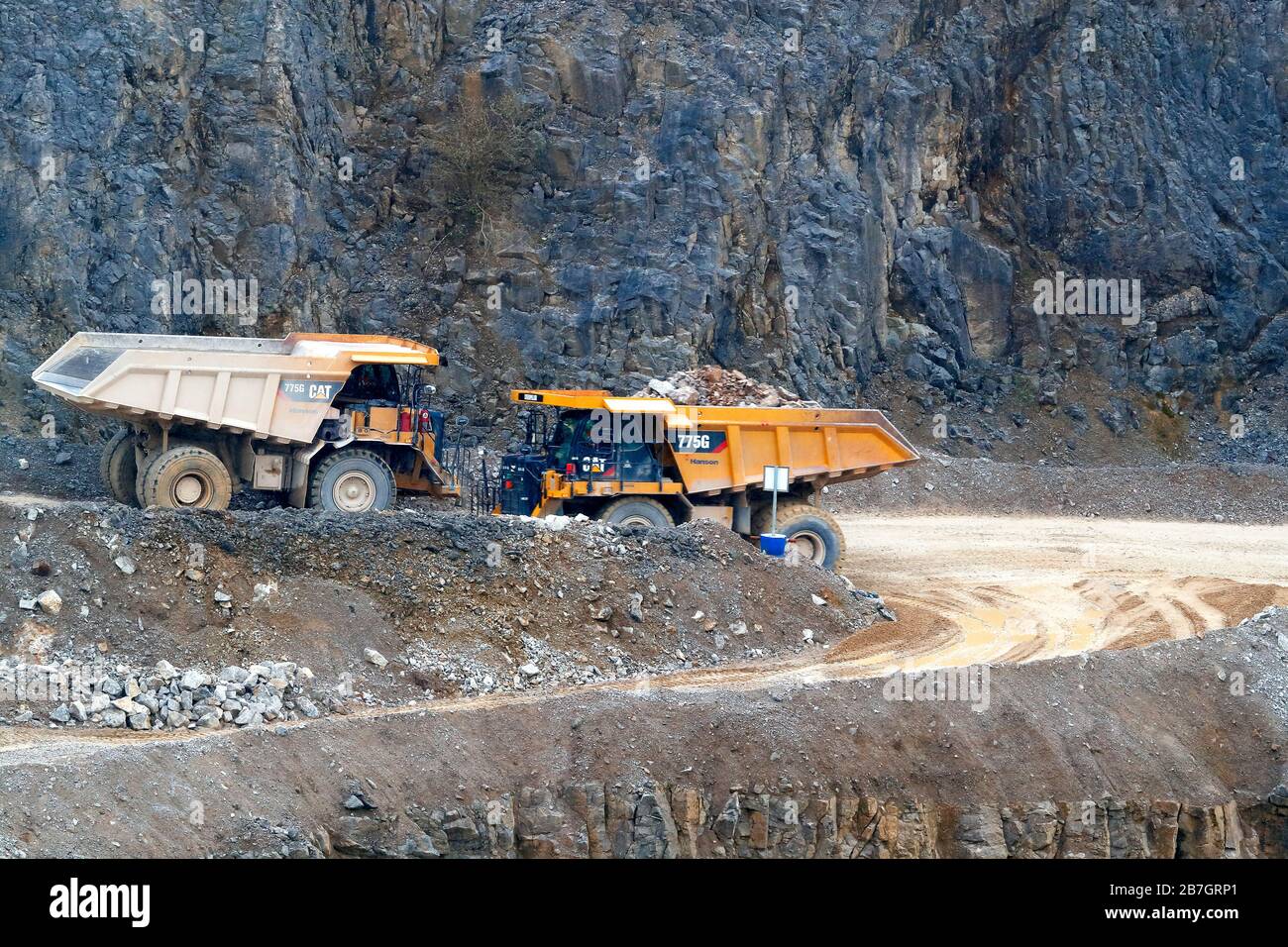 Two Caterpillar 775G trucks passing each other in Coldstones Quarry, Greenhow Hill, Niddedale in North Yorkshire. Stock Photo