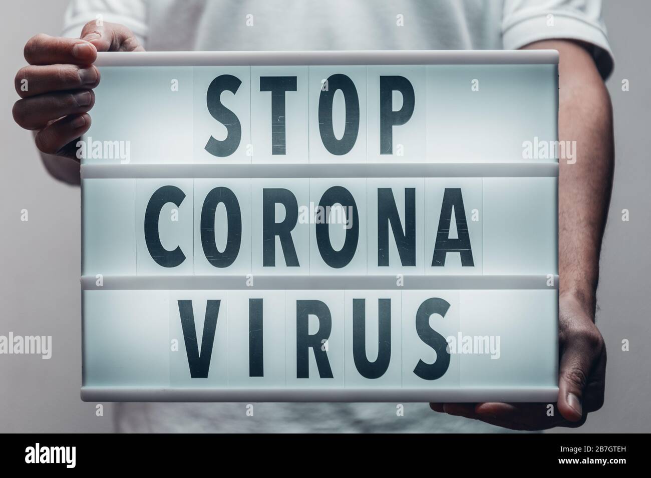 Adult male holding a lightbox text with a message 'Stop Corona Virus' written. Stock Photo