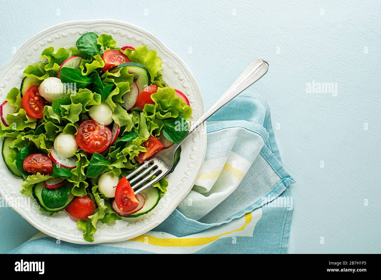 Healthy Green salad meal with mozzarella cheese and tomato on blue table background Stock Photo