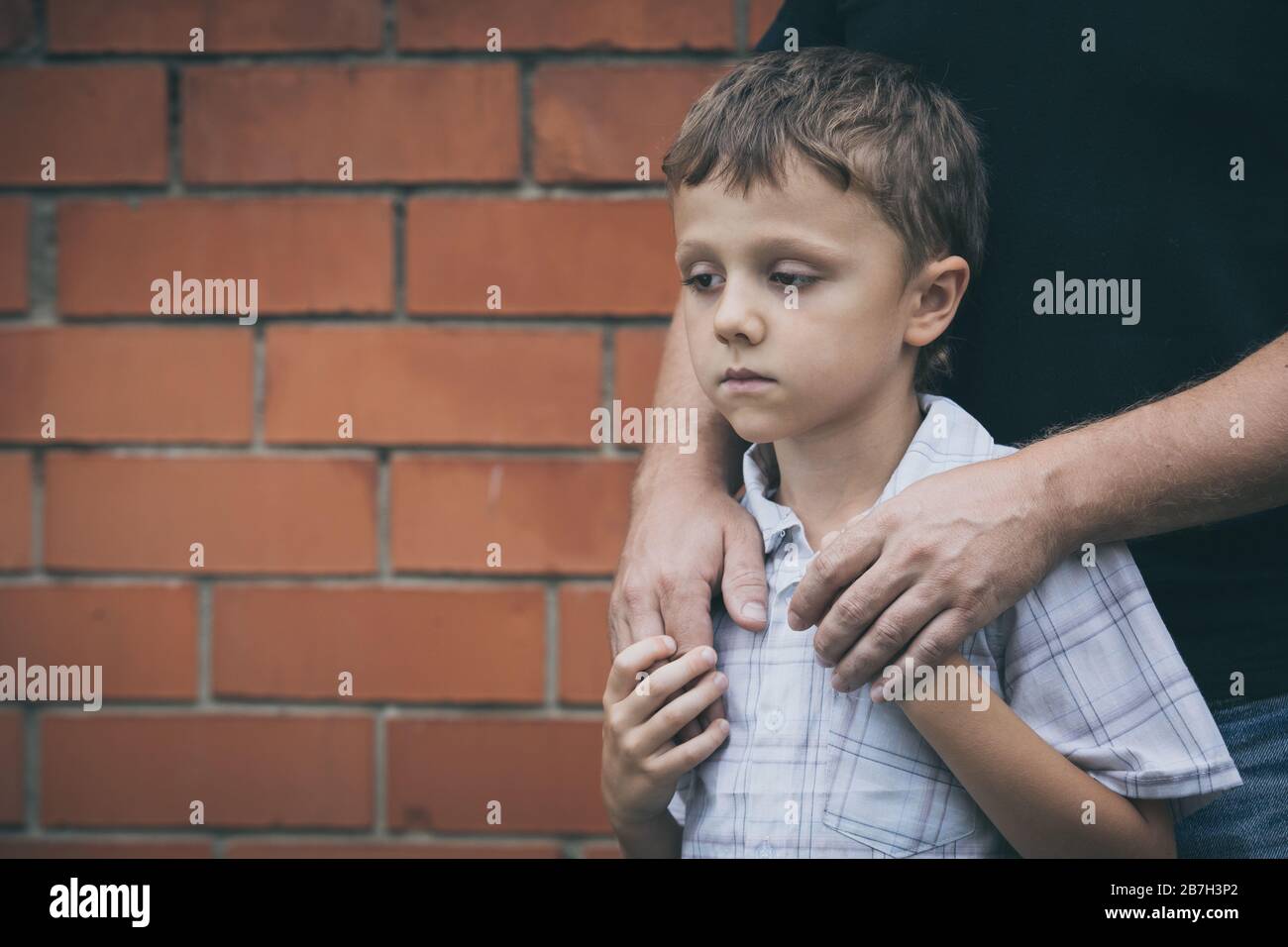 Portrait of young sad little boy and father standing outdoors at the day time. Concept of sorrow. Stock Photo