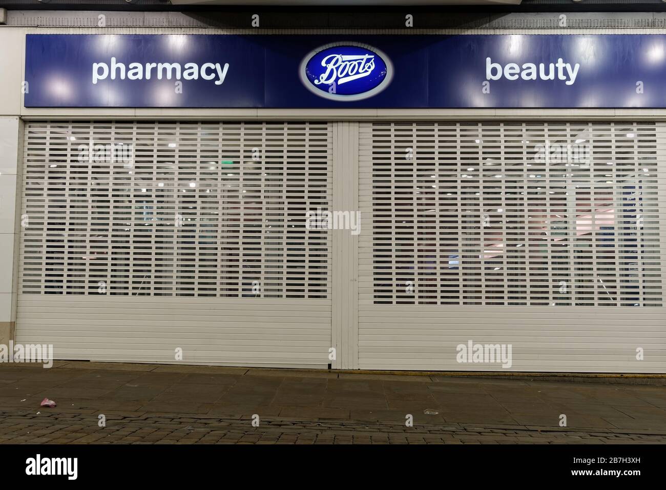 Manchester, UK Boots pharmacy chain closed store entrance. Night view of window store facade of