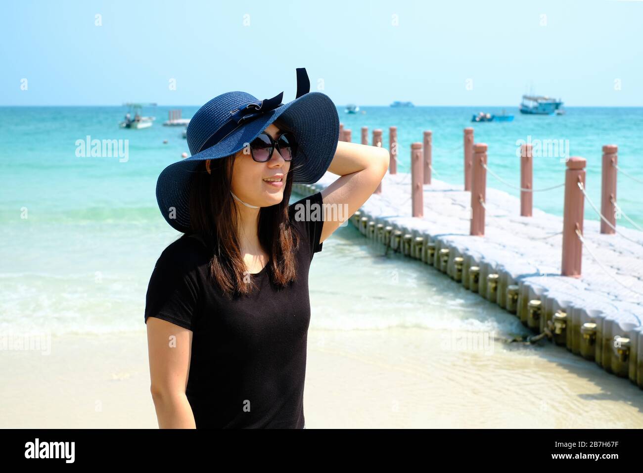 Portrait of Asian woman wearing blue hat smiling on the beach of Samed Island, Thailand. Stock Photo