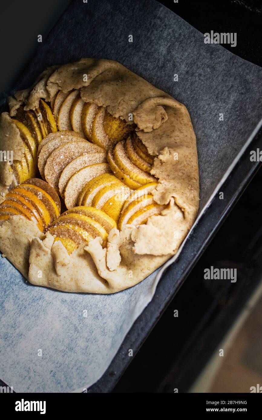 Raw apple galette - pie on white baking parchment. Copy space, flat lay. Stock Photo