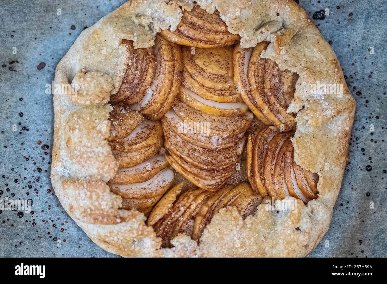 Apple galette - pie on baking parchment and dark background. Copy space, flat lay. Stock Photo