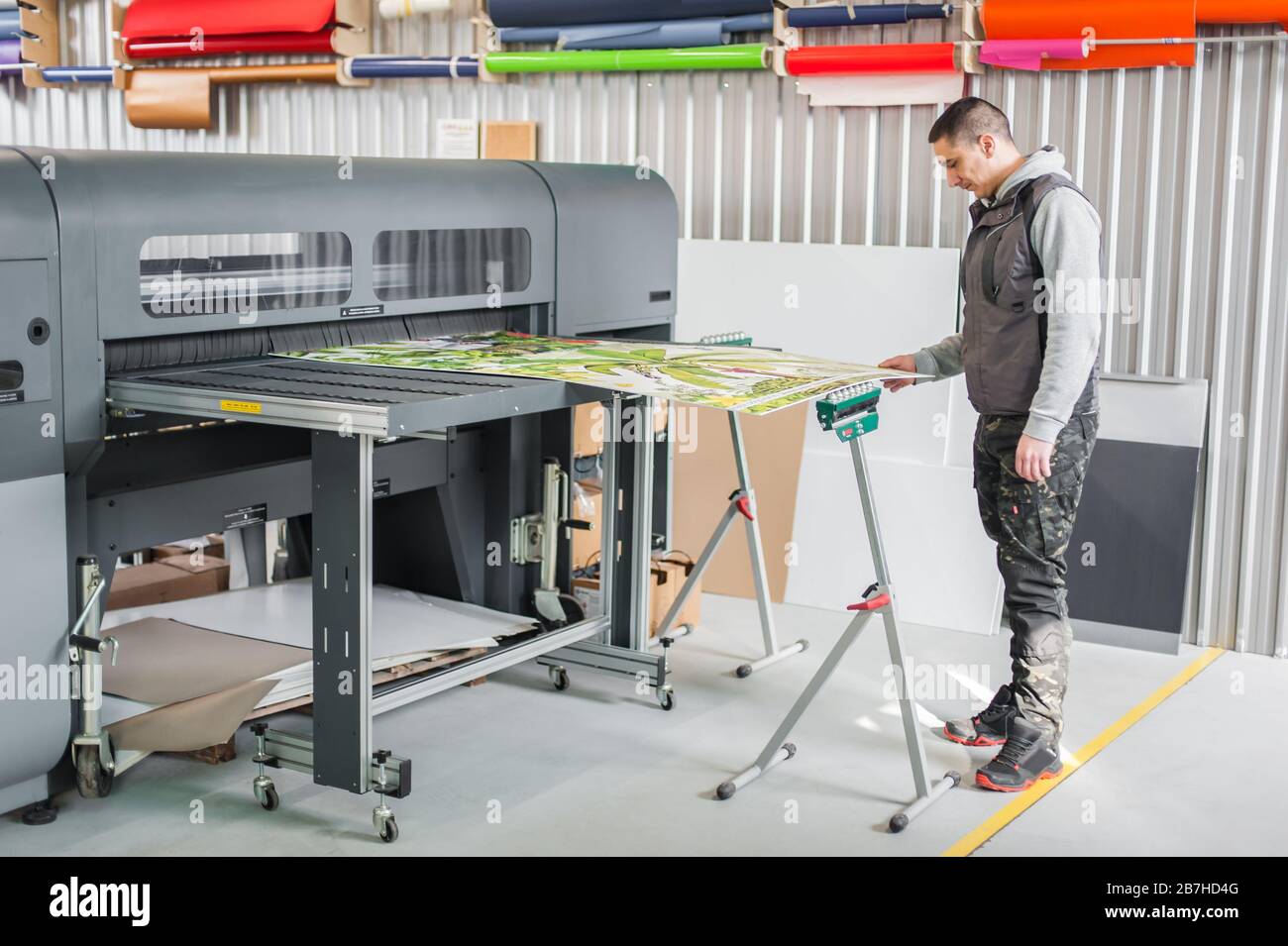 Technician worker operator works on large premium industrial printer