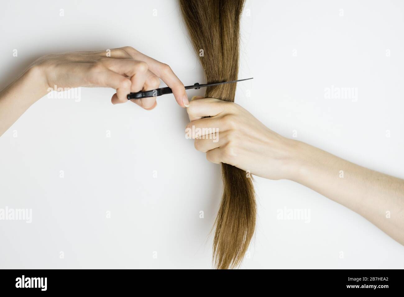 Upset woman cuts her long straight hair with scissors Stock Photo