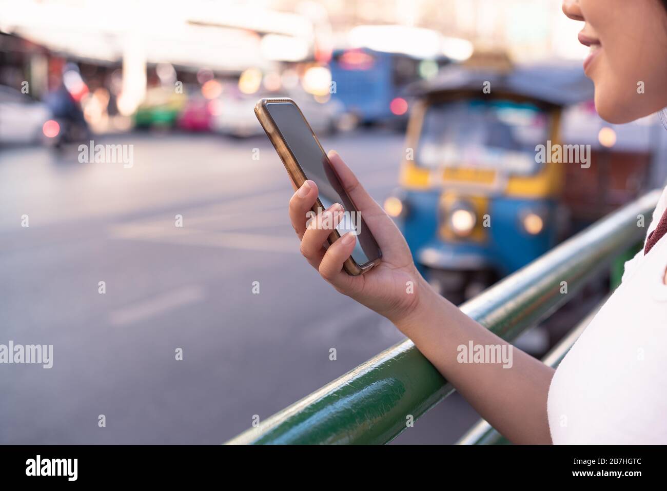 Diverse Asian hipster girl using mobile cell phone, in downtown urban city street - Millennial influencer woman holding smartphone making a video call - Technology, social tech and internet concept Stock Photo