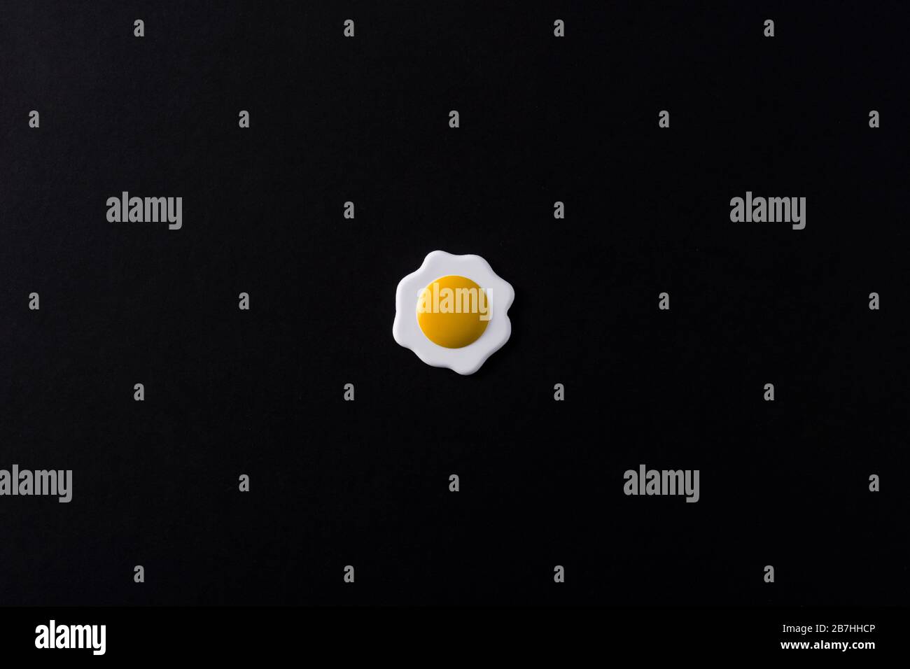 Minimalist fried egg on black background Stock Photo