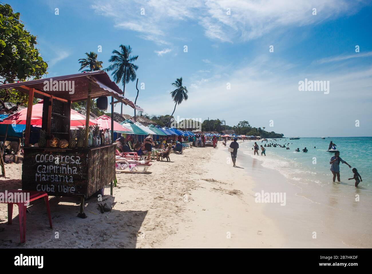 Cocktail stalls and deckchairs on the busy white-sanded beach and turquoise waters of Baru Island off the Caribbean coast of Cartagena, Colombia Stock Photo