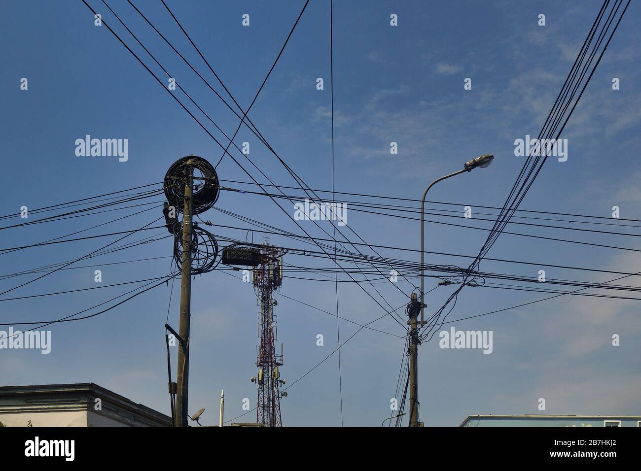 Tangle of electrical and telephone cables between poles in cities of