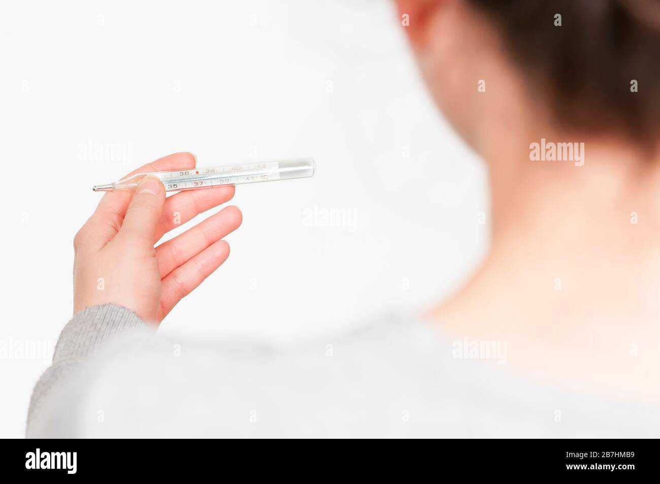 caucasian brunette woman with thermometer. white background SARS-CoV-2, Coronavirus, COVID-19. Stock Photo